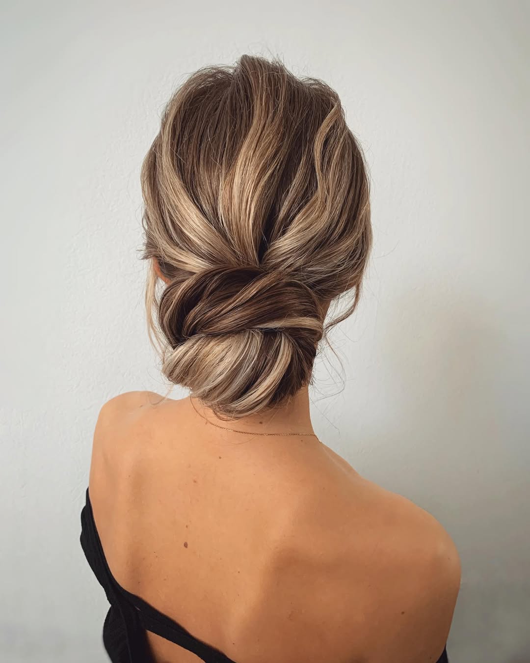 Blonde woman with effortless summer hairstyle 2026, featuring loose waves, a denim shirt, and white jeans, casually styled for a beach vacation.