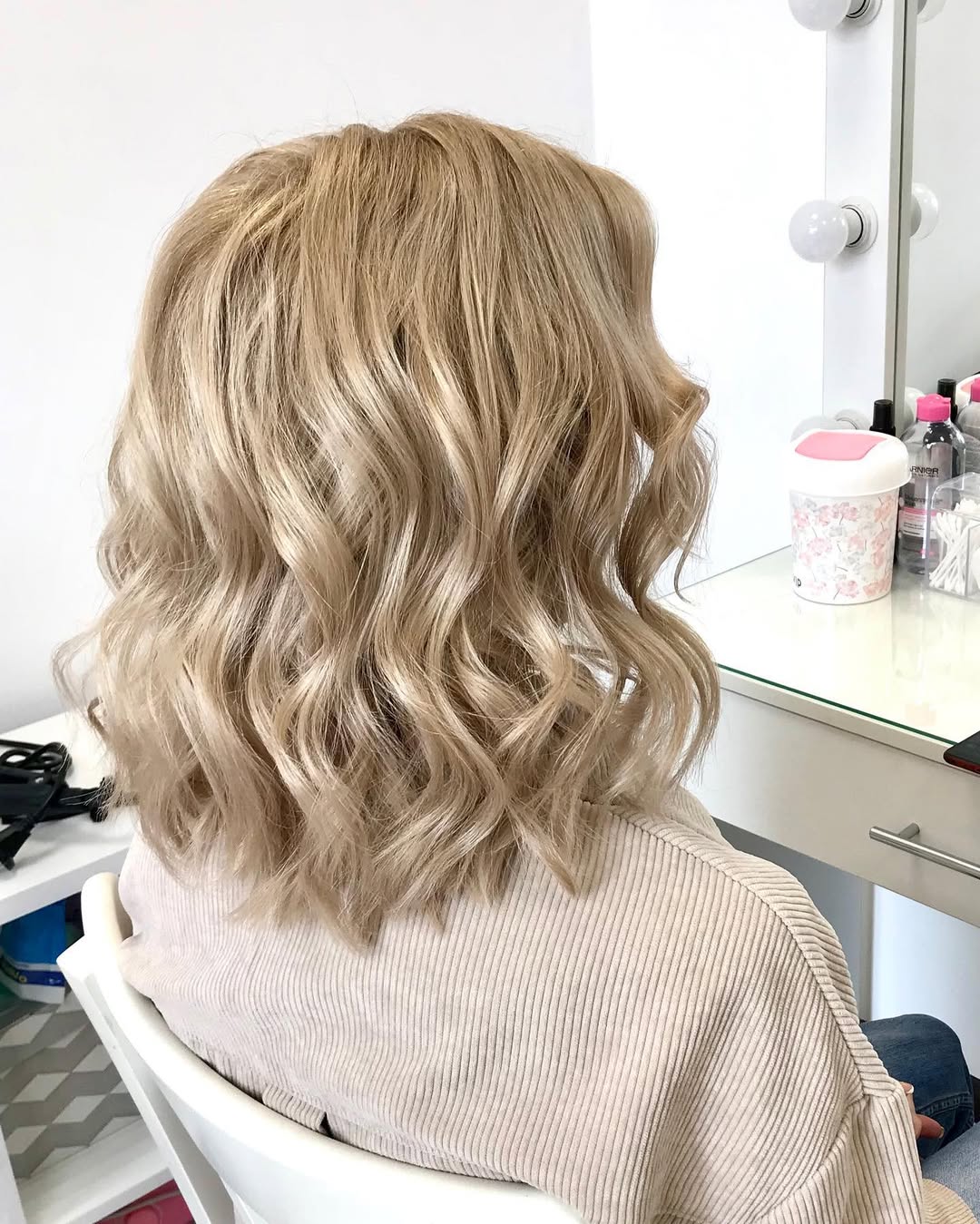 Woman with effortless summer hairstyles 2026, sporting a casual oversized white linen shirt and denim shorts for a sunny day.