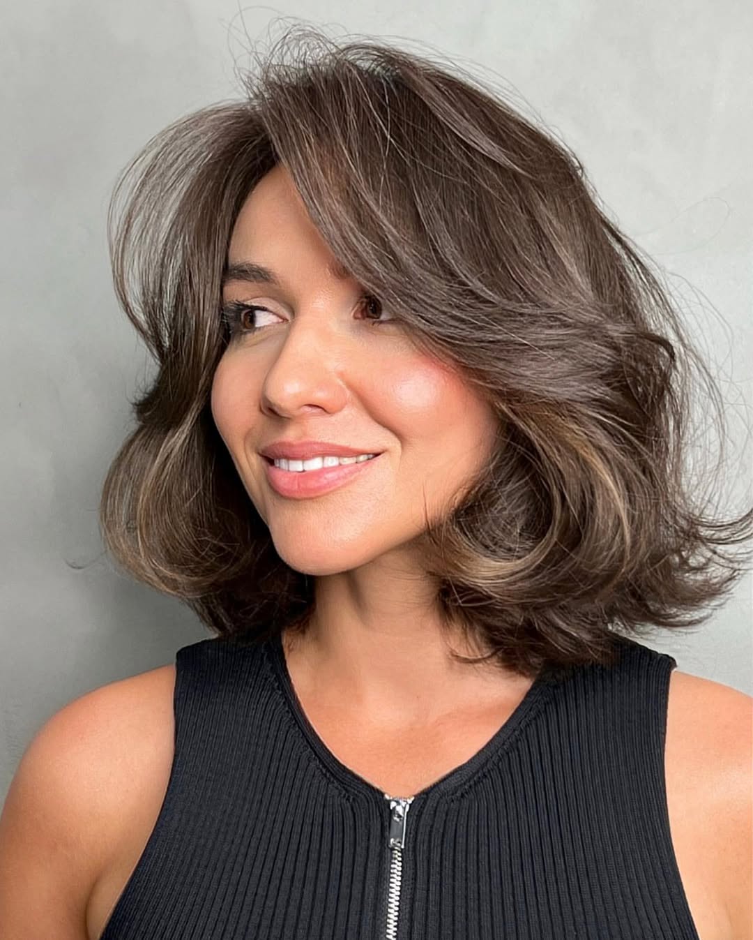 Close-up of a woman with a casual, wavy half-updo, showcasing natural, sun-kissed blonde hair perfect for effortless summer hairstyles 2026. A few face-framing strands soften the look.