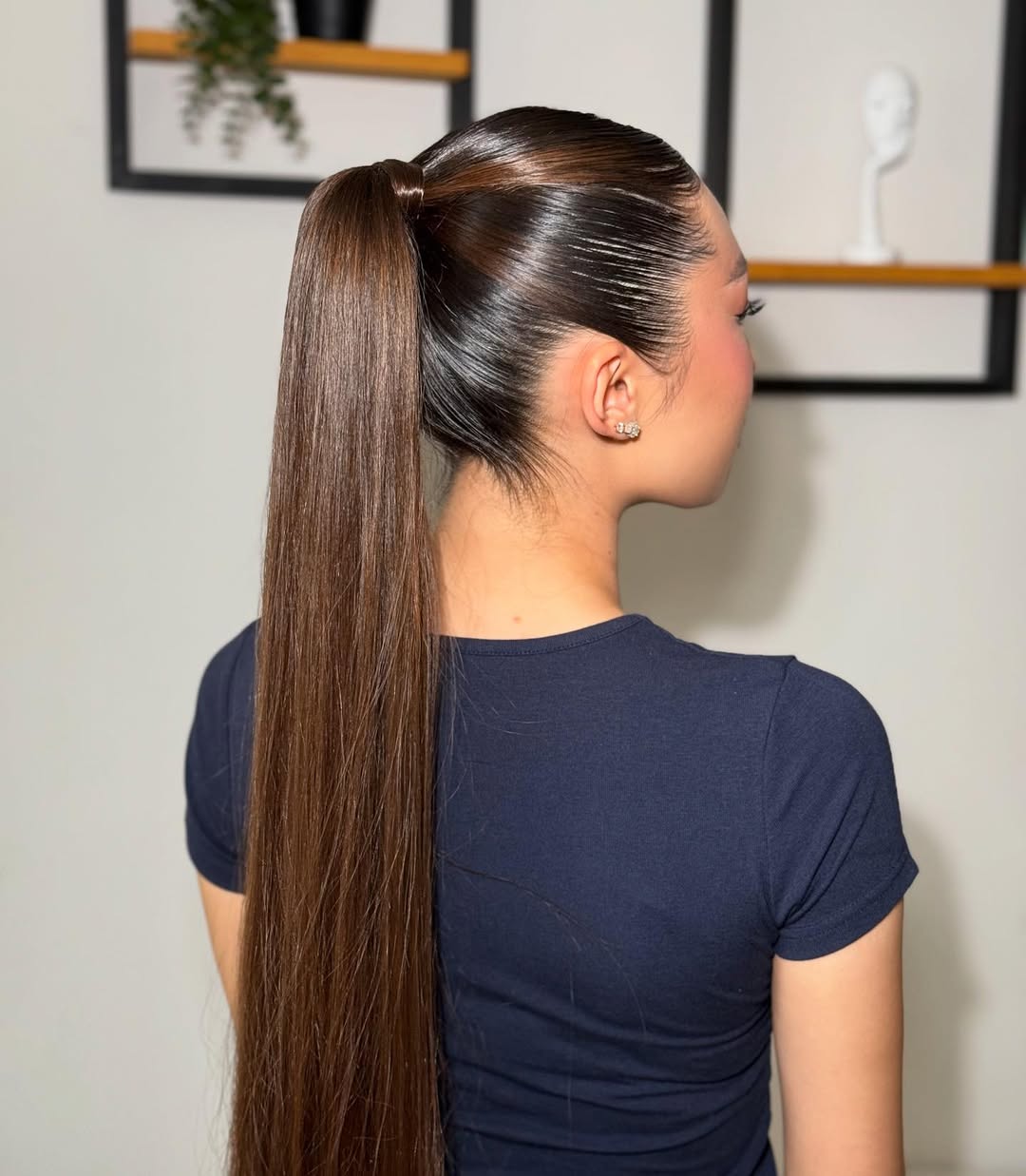 Woman with long, wavy blonde hair styled in a loose low bun, showcasing effortless summer hairstyles 2026. Perfect for a casual daytime look or beach outing, paired with a white linen top.
