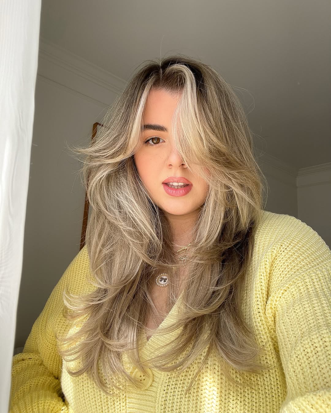 A woman with a stylish, face-framing bob, perfect for flattering summer haircuts 2026. Her light brown hair is styled with subtle waves, complementing her casual denim jacket and white top for a chic, everyday look.