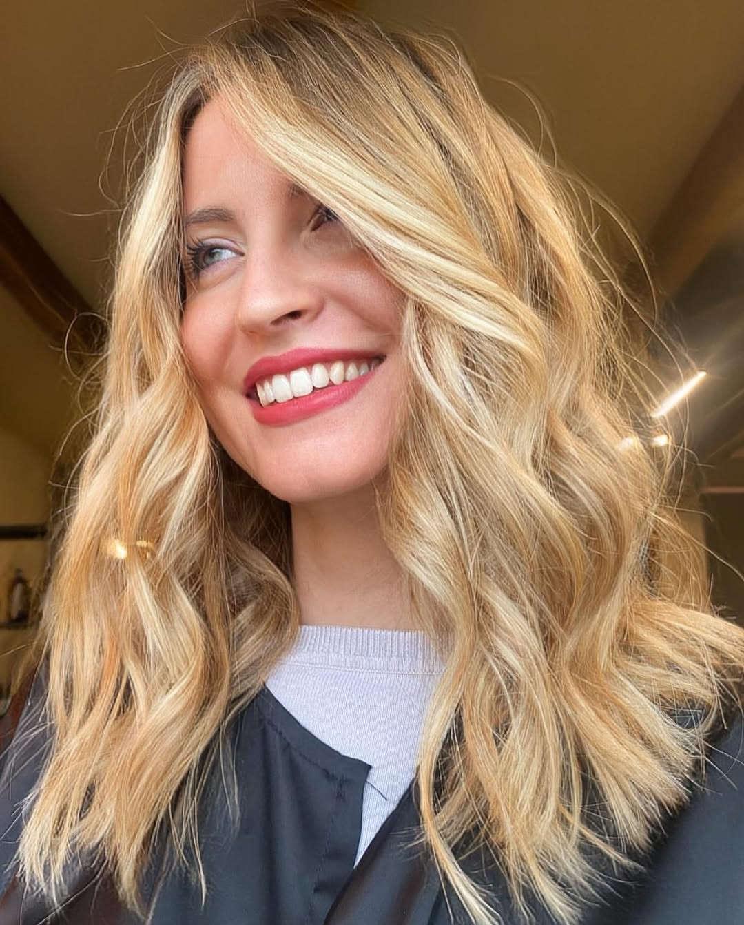 Woman showcasing golden balayage summer 2026 hair, wearing a breezy white linen dress with a straw hat and sandals for a perfect beach day outfit.