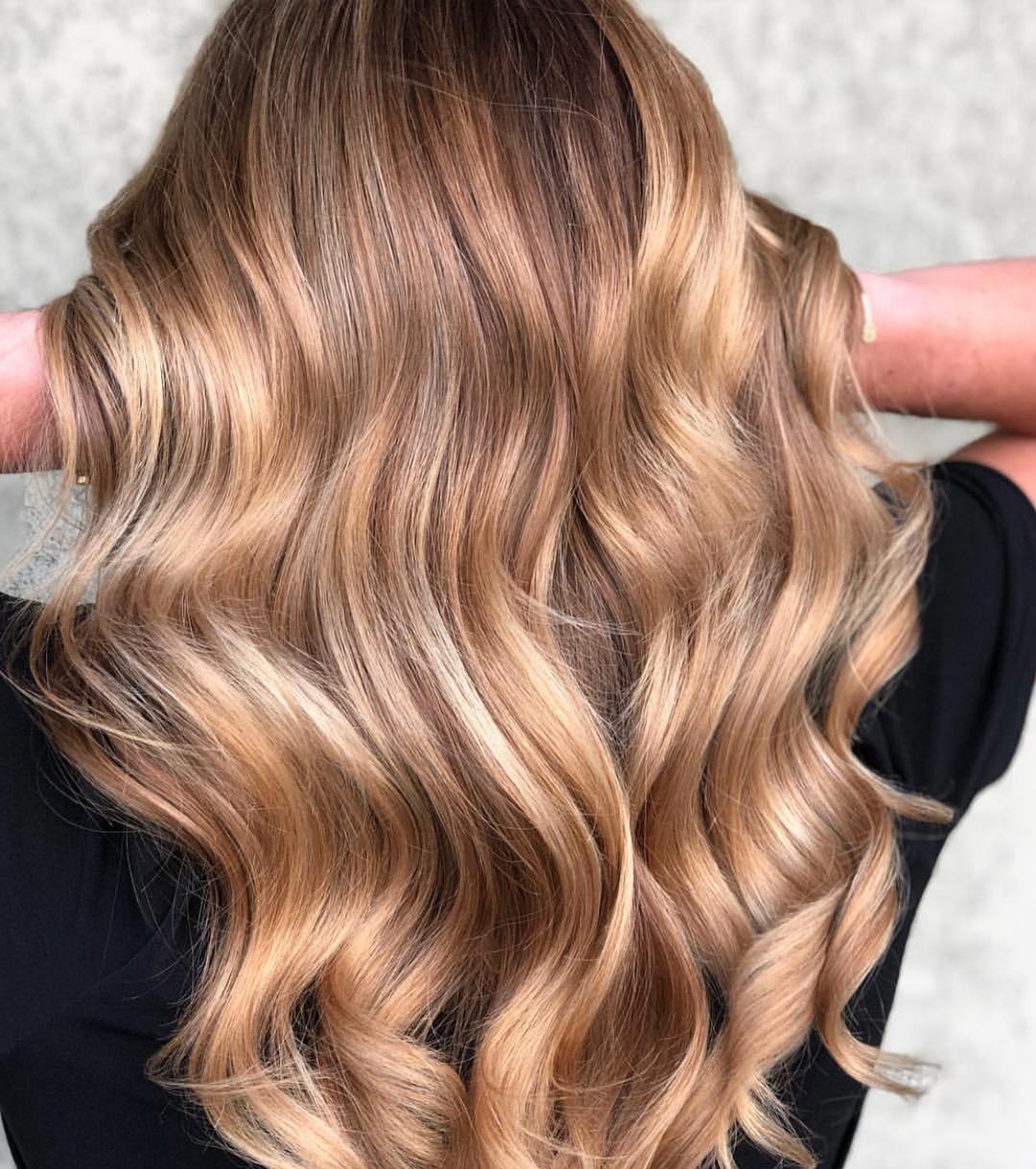 Close-up of a woman with stunning golden balayage summer 2026 hair, styled in loose waves, paired with a vibrant floral sundress perfect for a casual sunny day outing.