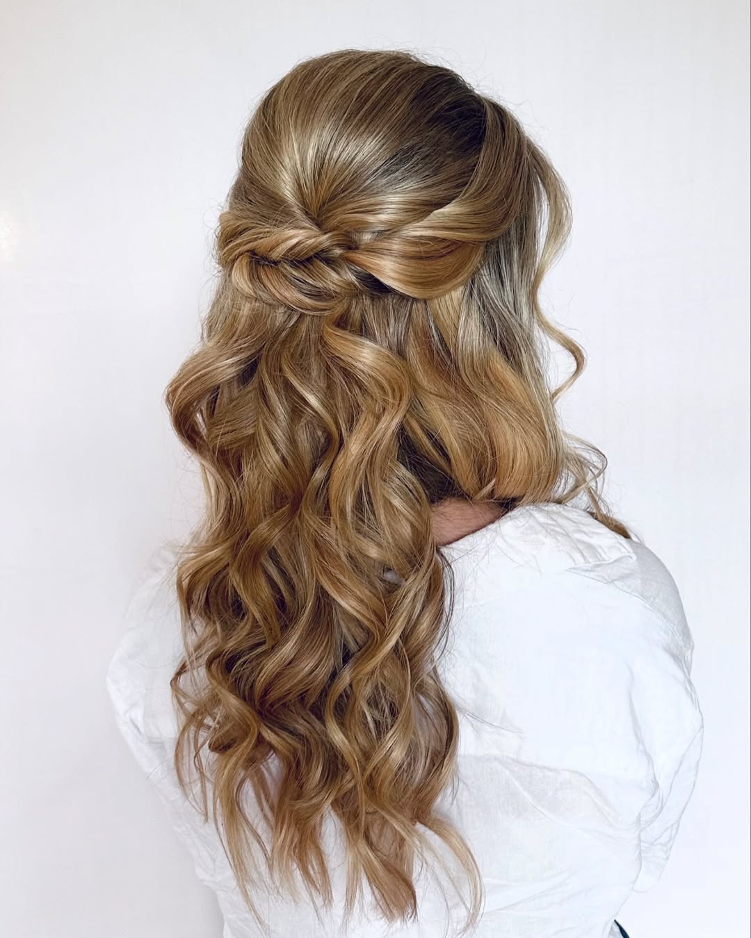 Close-up of a elegant blonde woman with a half-up braided hairstyle adorned with delicate white flowers, perfect for an outdoor wedding hair summer 2026. The look is soft and romantic.