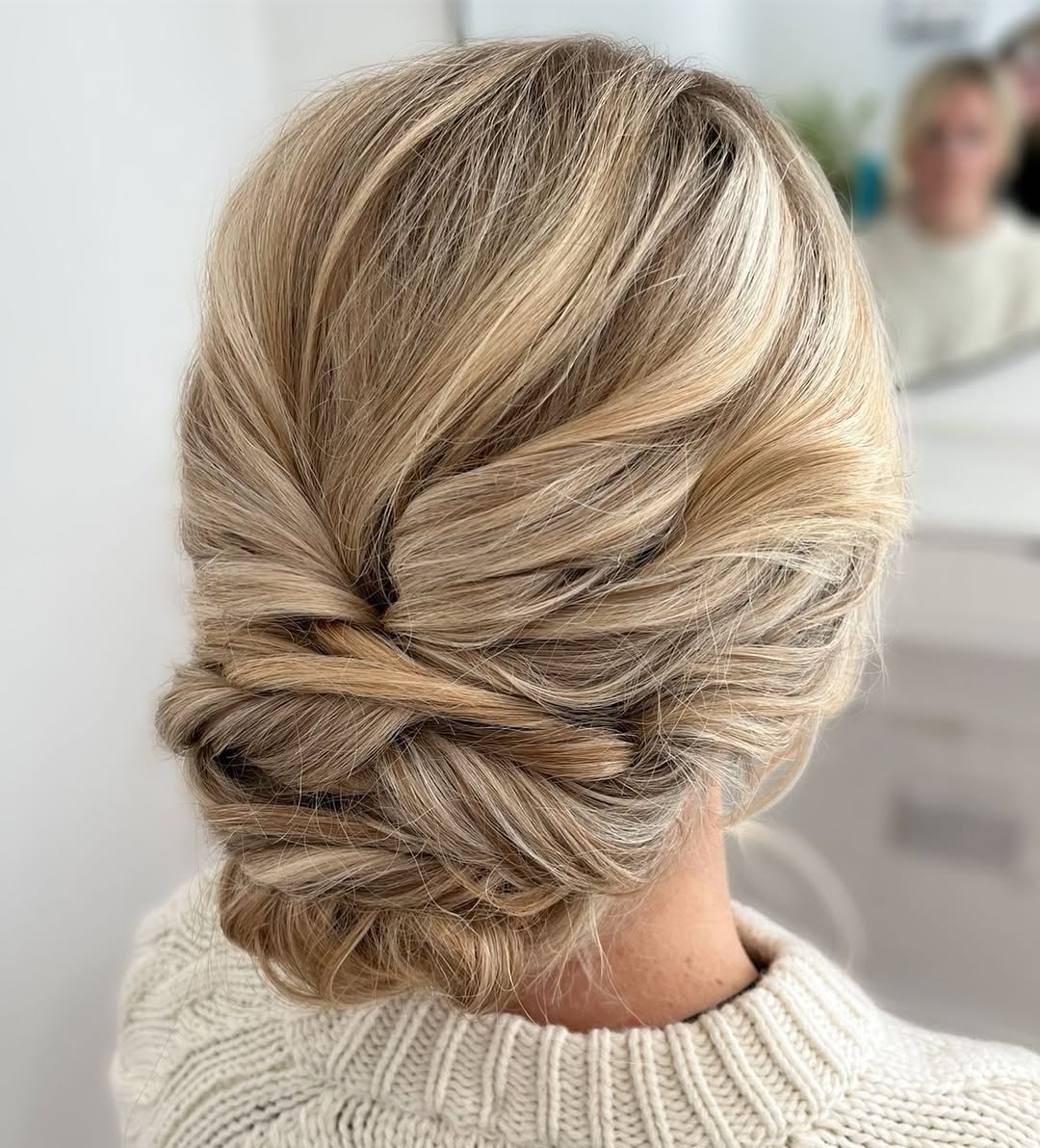 Close-up of a woman with braided updo hair, adorned with delicate white flowers, perfect for outdoor wedding hair summer 2026.