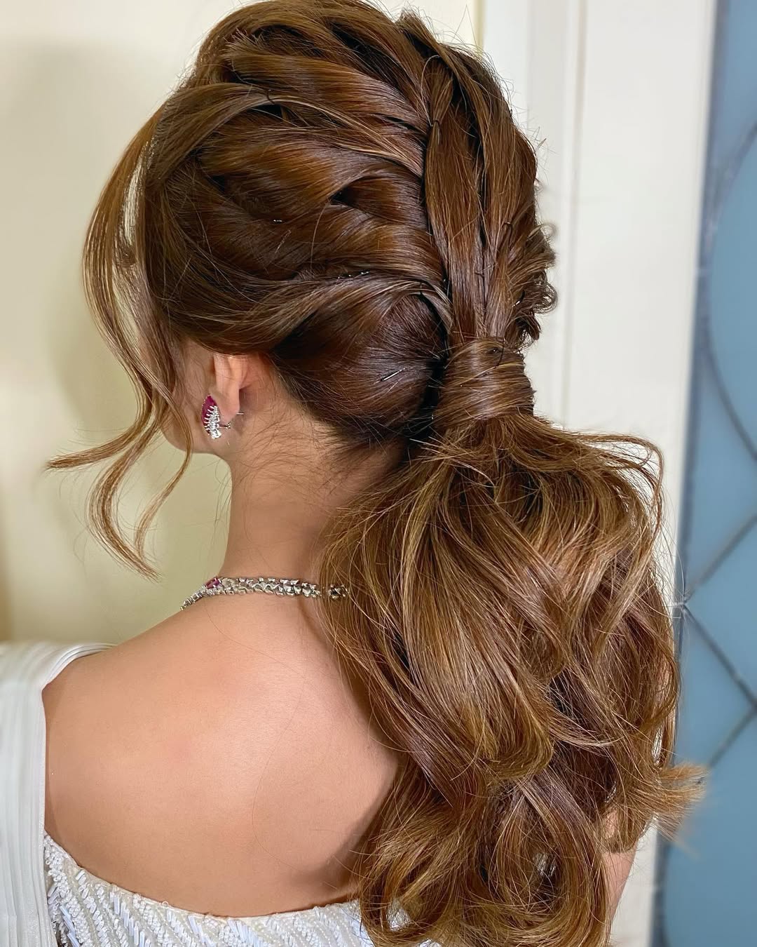 Beautiful blonde woman with a soft, romantic updo, perfect outdoor wedding hair summer 2026. Her hair is loosely braided with delicate white floral accents, ideal for a garden or beach wedding.