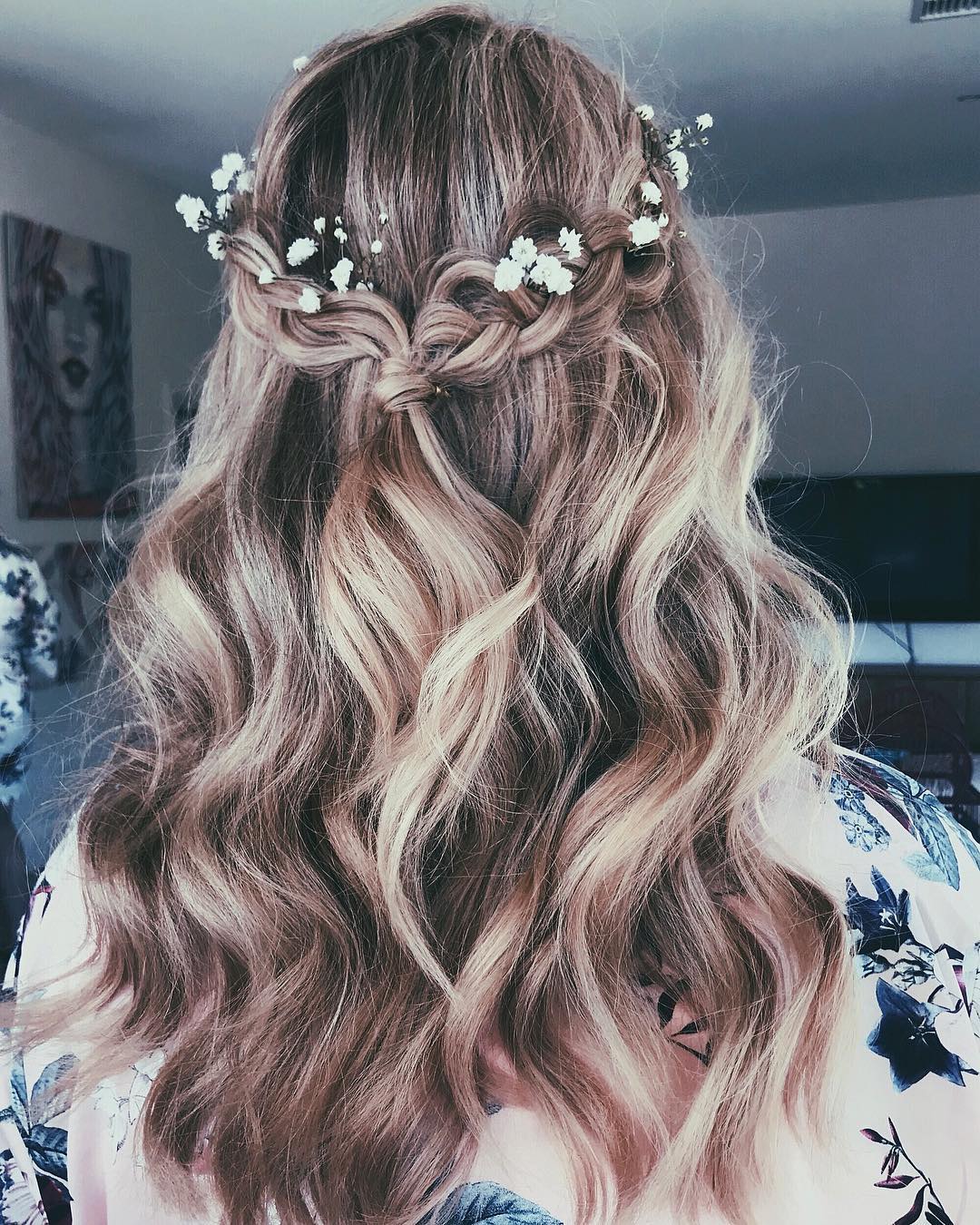 Elegant brunette woman with a loose, voluminous low bun, adorned with delicate white floral accessories perfect for outdoor wedding hair summer 2026.