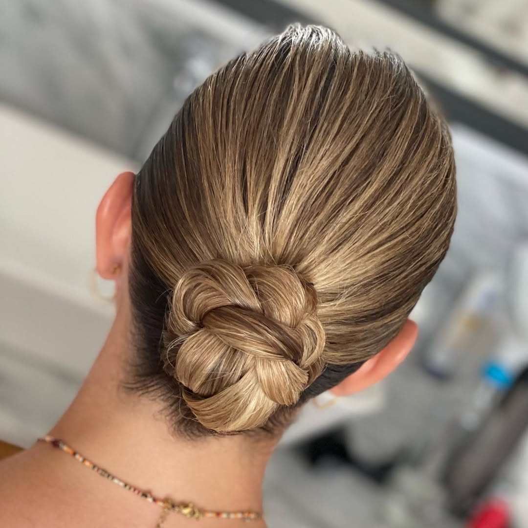 Elegant brunette bride with a soft, voluminous half-updo, adorned with delicate white floral accessories, perfect for an outdoor wedding hair summer 2026. Her hair flows naturally over her shoulders, complementing a simple white dress.