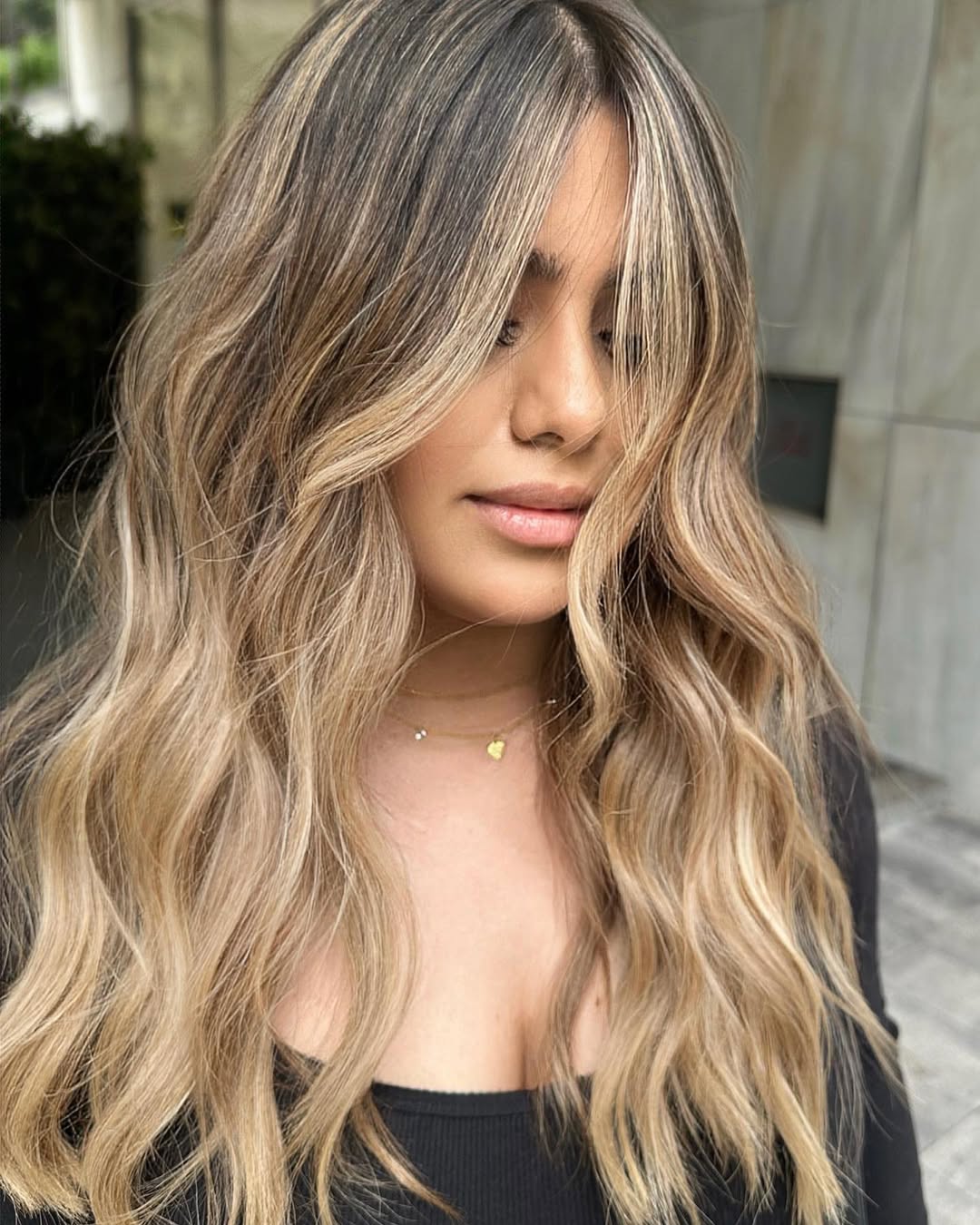 Close-up of a woman's hair showcasing sun-kissed summer babylights balayage 2026, featuring golden blonde tones and soft, natural-looking highlights on dark blonde base, suitable for a bright, refreshed look.