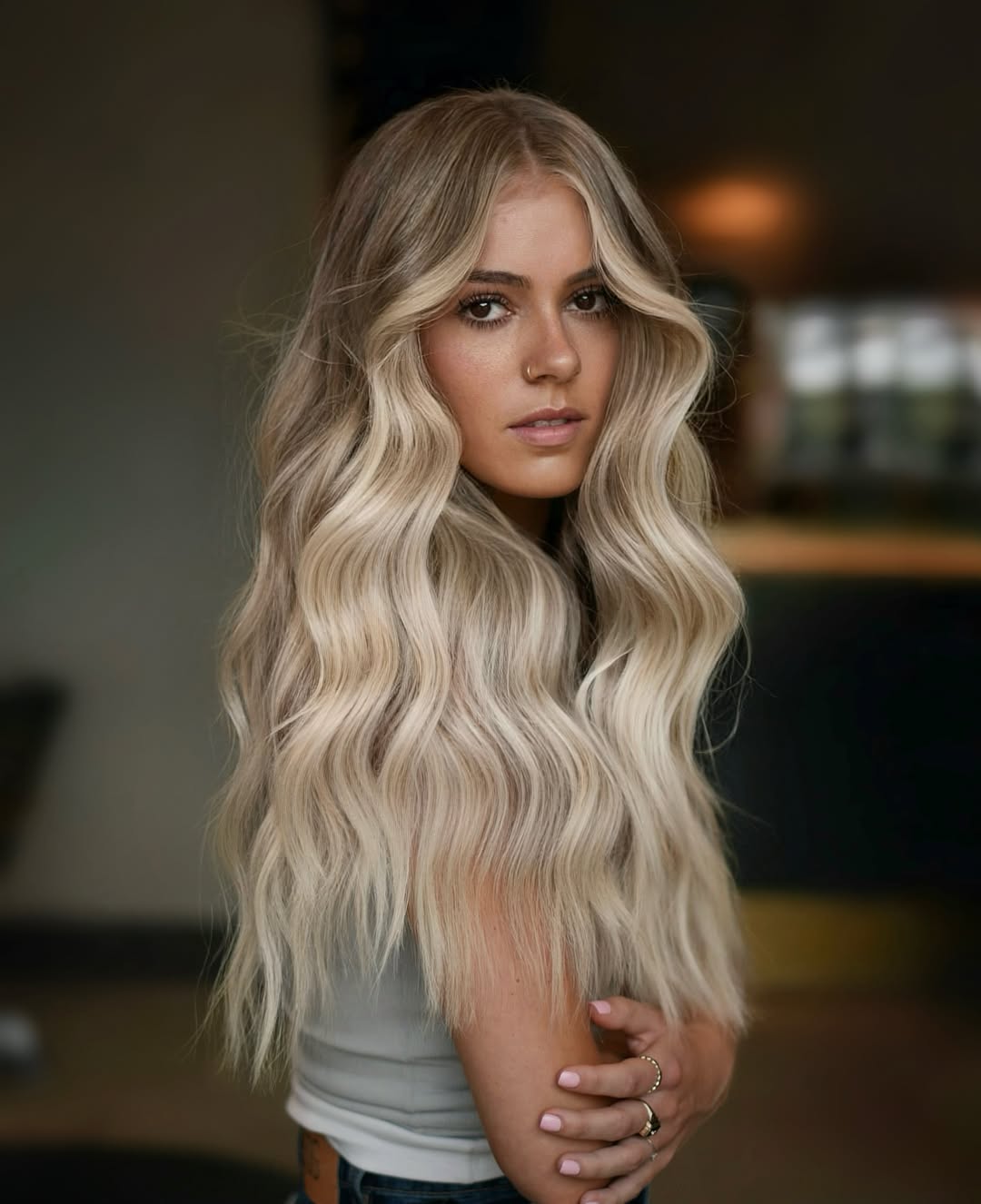Close-up of a woman with long, sun-kissed brown hair featuring delicate summer babylights balayage 2026, creating a natural, soft highlight effect.