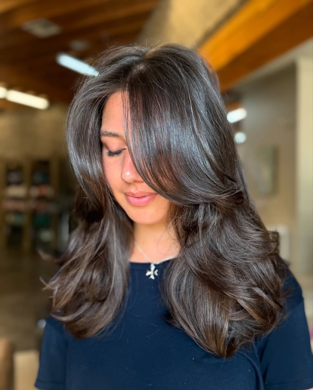 A woman with vibrant honey blonde hair, perfectly highlighted for a sun-kissed look, showcasing popular summer hair color options 2026. Her hair is styled in loose waves, complementing a casual beach-ready outfit.