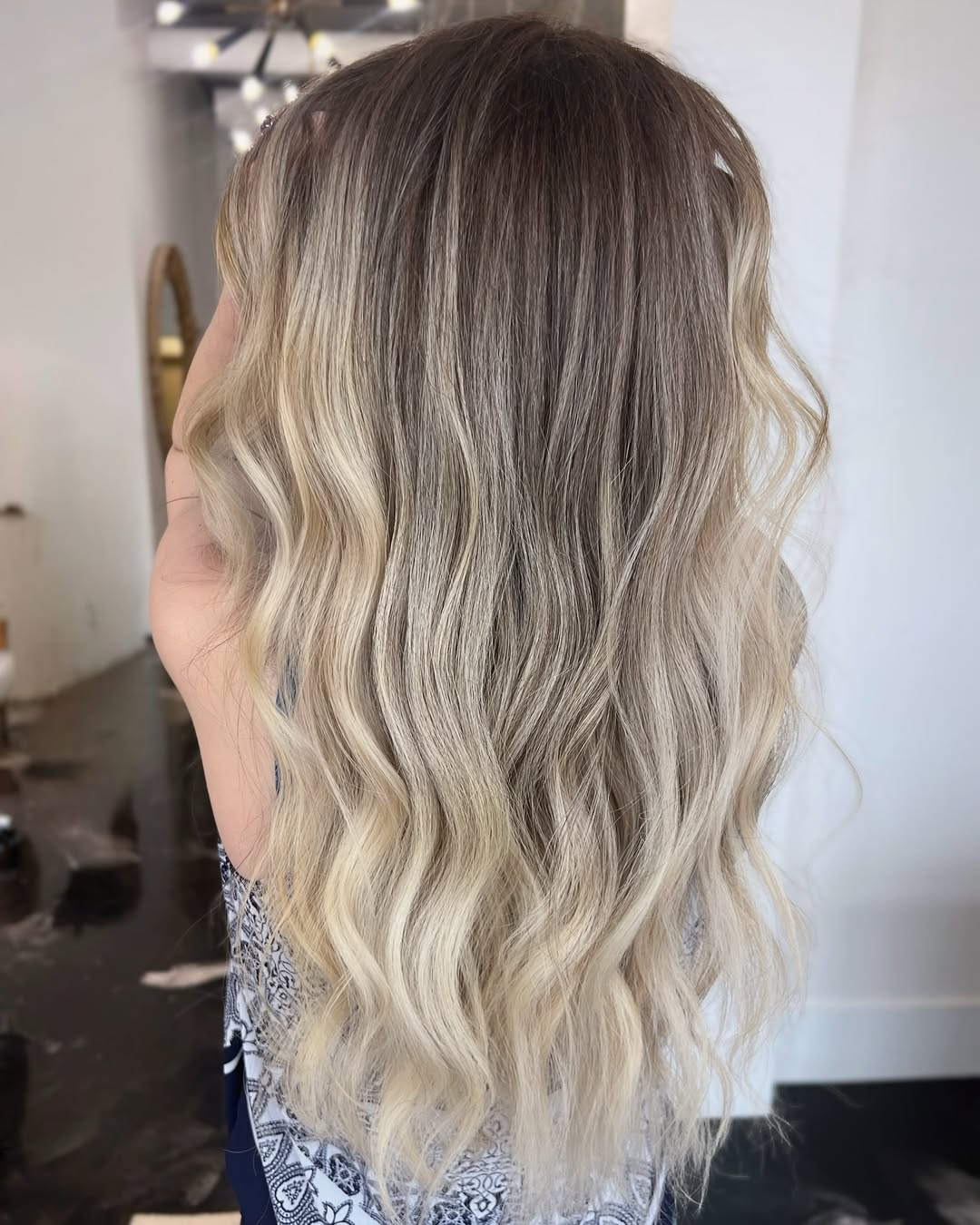 Close-up of a blonde woman with sun-kissed highlights, wearing a white straw hat, enjoying a summer day. Perfect example of summer hair ideas for blondes.