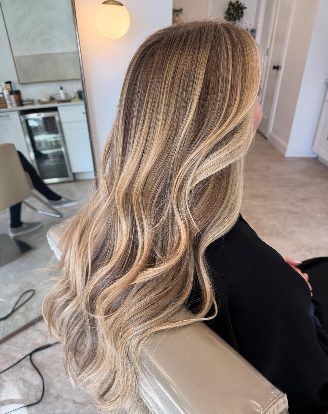 Close-up of a blonde woman with long, sun-kissed wavy hair, styled with a casual half-up bun, perfect for summer hair ideas for blondes 2026. Her hair has subtle highlights catching the light.