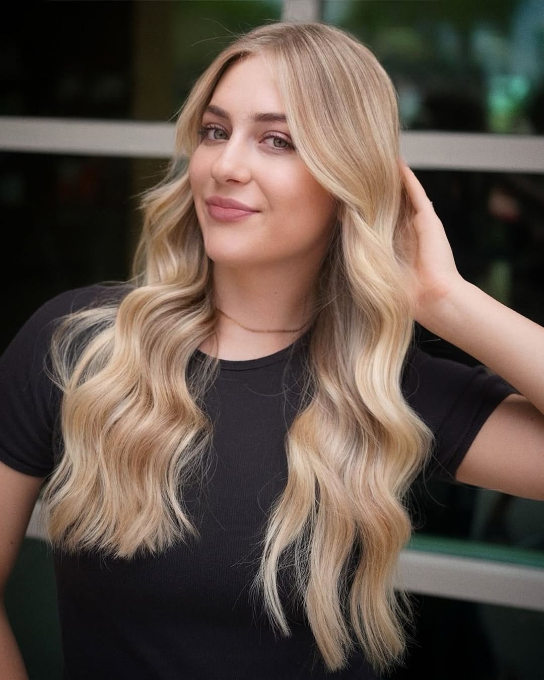 Blonde woman with long, textured, waist-length waves, styled loosely for a casual summer look, showcasing beautiful summer hair ideas for blondes.