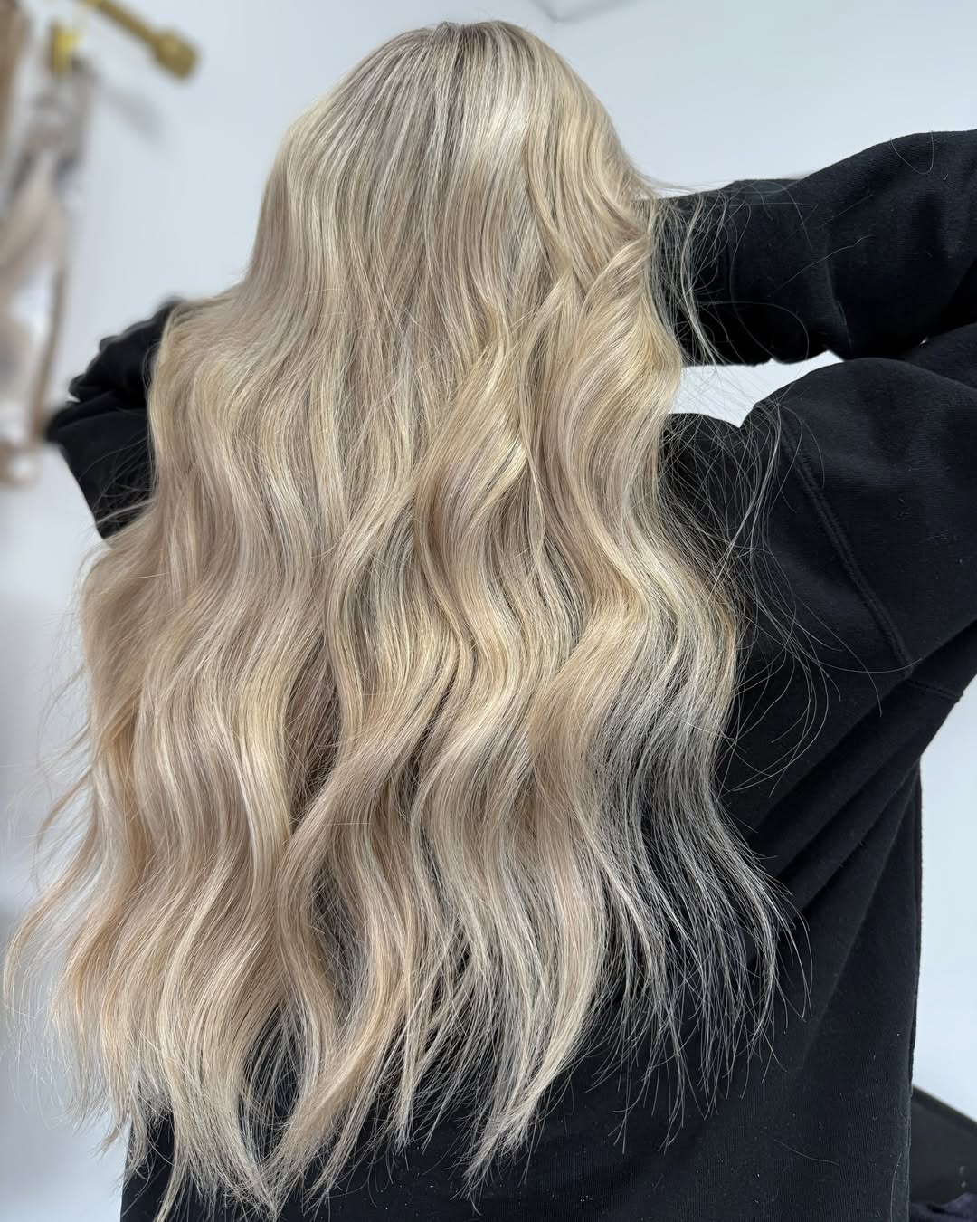 Blonde woman with a chic messy bun, perfect for summer hair ideas for blondes. She wears a white off-the-shoulder top for a casual daytime look.