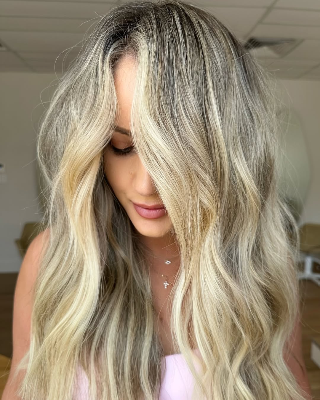 Close-up of a blonde woman with a vibrant, sun-kissed ombre balayage, framing her face with soft waves, perfect for summer hair ideas for blondes. Her hair showcases brighter ends blending seamlessly from darker roots.
