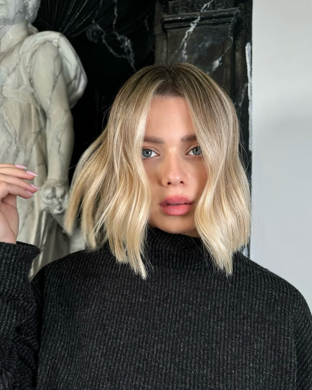 A blonde woman with sun-kissed wavy hair, perfect for summer. This beautiful updo features loose face-framing strands, ideal for beach days or casual outings. Explore summer hair ideas for blondes.