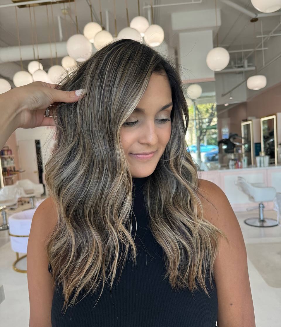 A woman with a chic, shoulder-length bob, styled with soft waves, perfect for summer haircuts inspiration 2026. This elegant cut features sun-kissed highlights, framing her face beautifully for a casual daytime look.