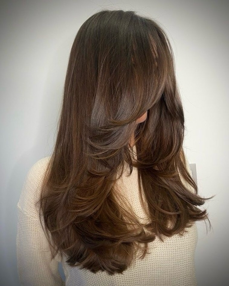 A woman confidently showcases a choppy, layered bob, a trendy haircut perfect for summer 2026, styled with light volume.