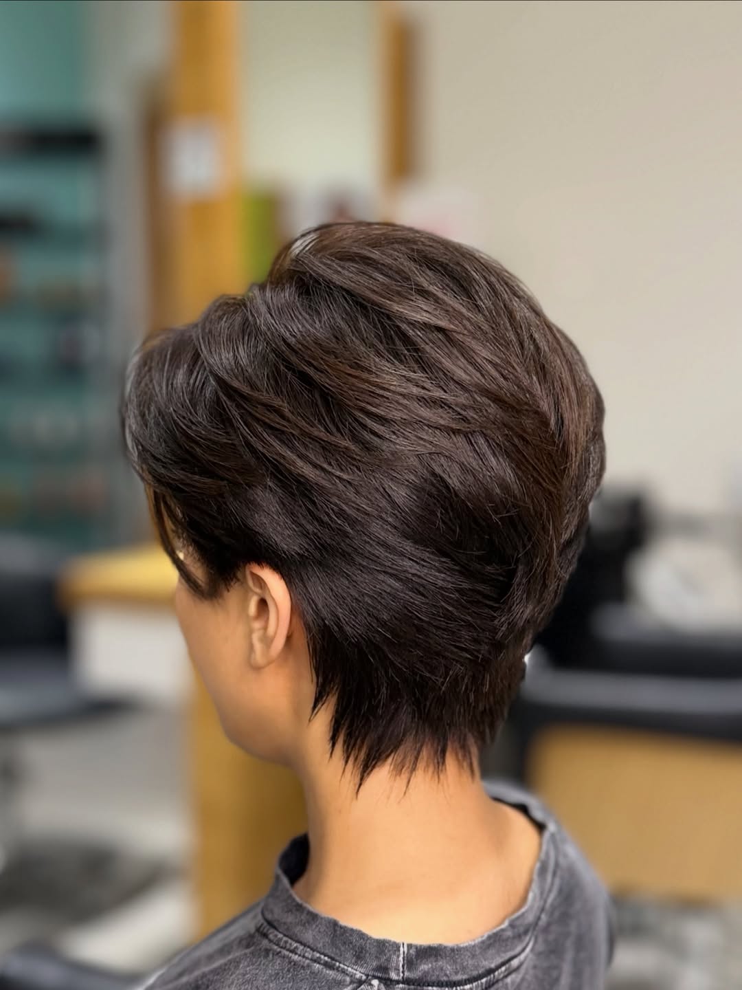 A woman confidently showcases a sleek, shoulder-length bob, a perfect trendy haircut for summer 2026, with a bright orange top and delicate gold jewelry.