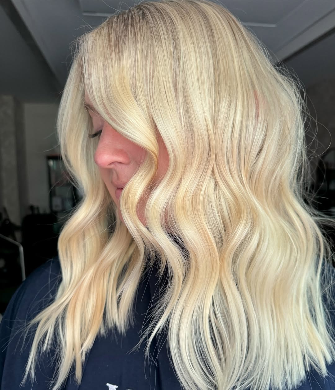 Woman with shimmering warm blonde hair styled with soft waves, wearing a white off-the-shoulder top for a perfect summer 2026 beach vacation look.