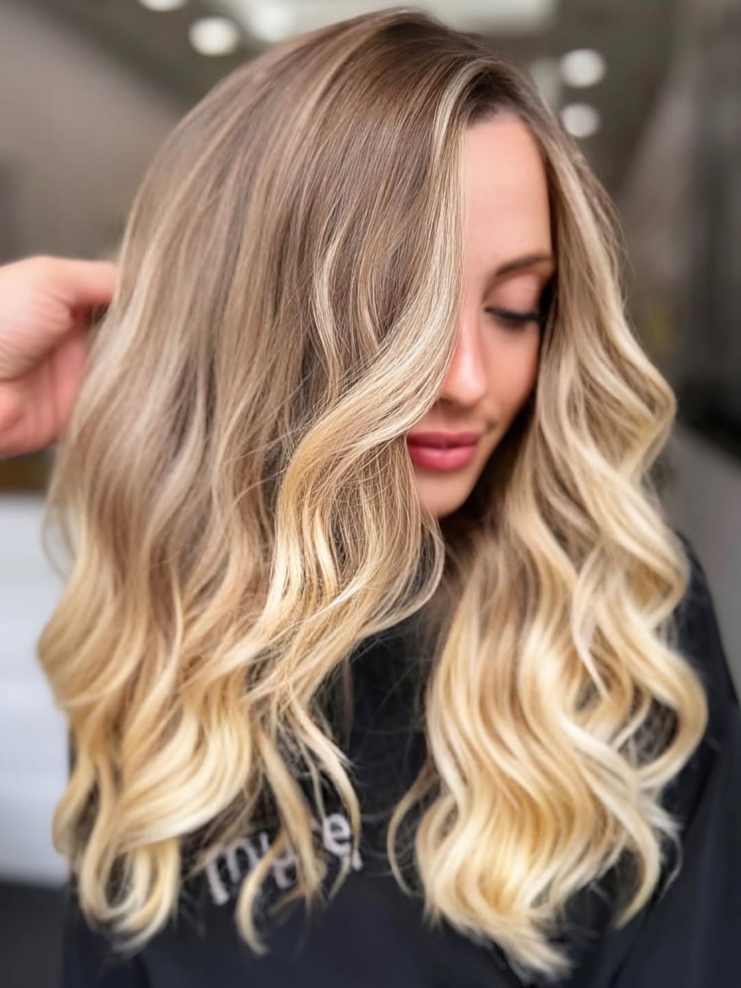 Woman with long, warm blonde hair in loose waves, wearing a white oversized linen shirt for a chic summer 2026 beach look.