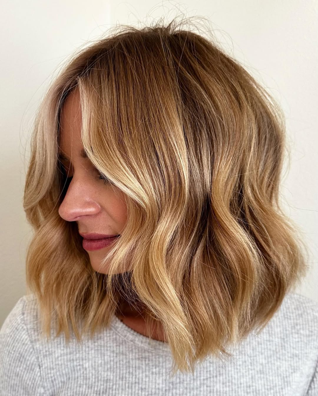 Woman showcasing warm blonde hair summer 2026, styled in soft waves with a flowy white sundress, ideal for beach or casual outings.