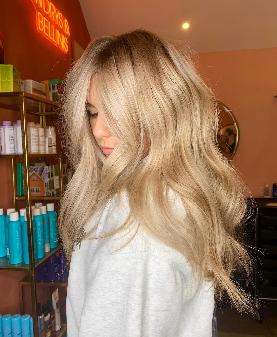Close-up of a smiling woman showcasing beautiful warm blonde hair for summer 2026, styled in soft waves with sun-kissed highlights, perfect for a sunny day.