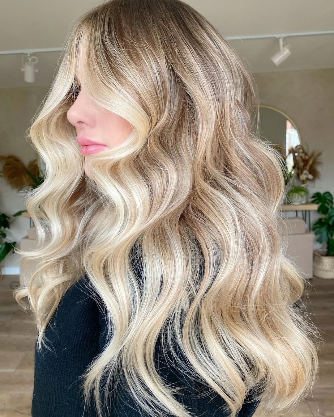 Close-up of a woman with radiant warm blonde hair summer 2026, styled in soft waves with sun-kissed highlights, perfect for a casual sunny day. Her hair frames her smiling face beautifully.