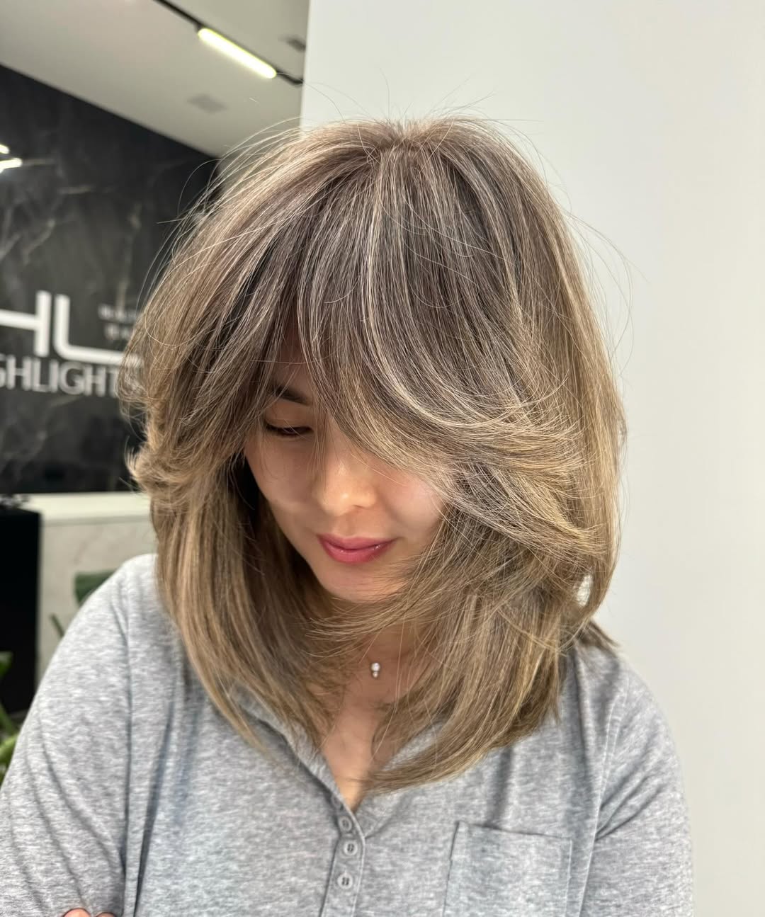 A woman with a chic, layered bob haircut, perfect for women haircuts summer 2026, posing outdoors in a casual white top.