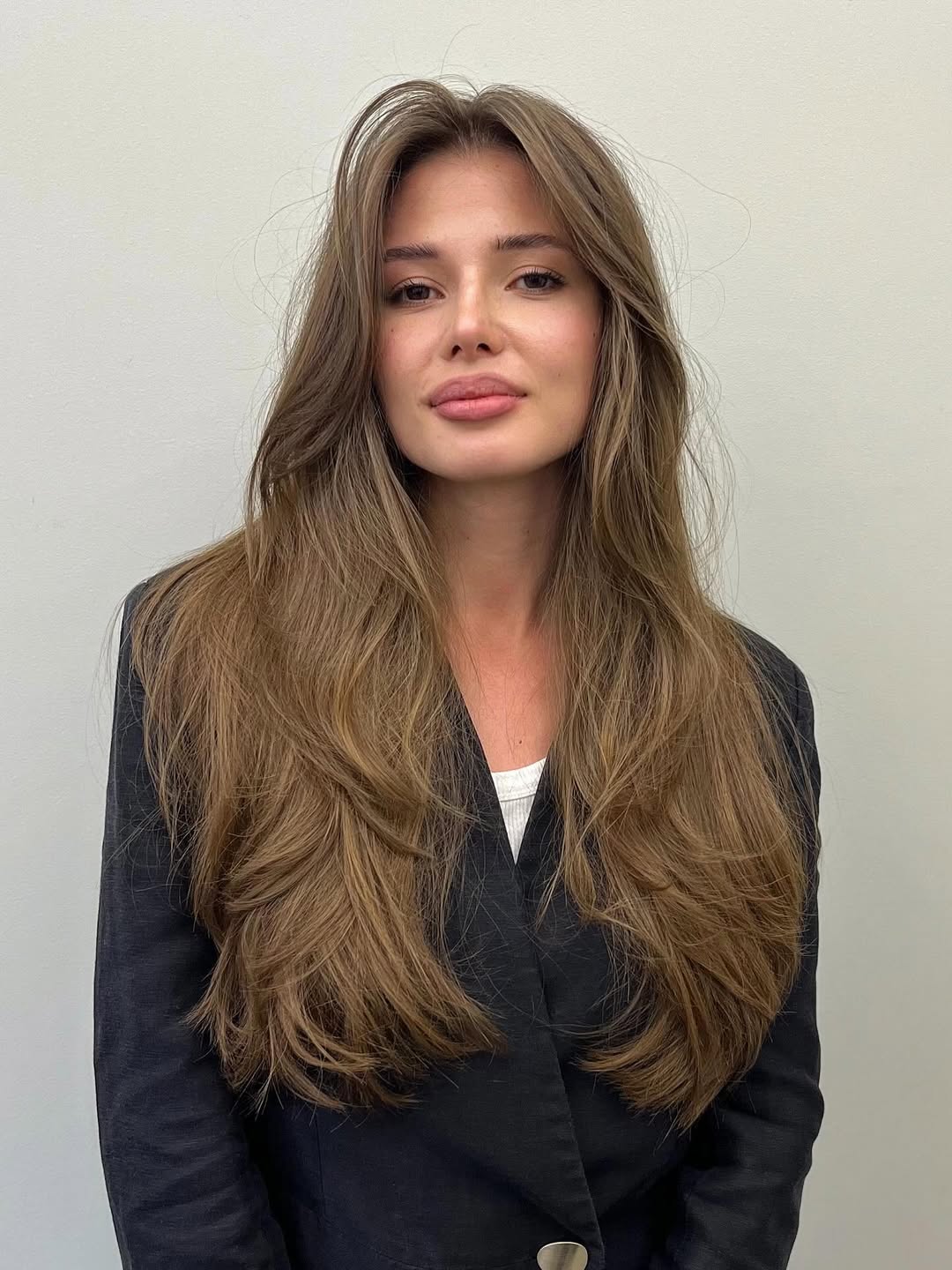 A woman with a chic, short wavy bob, perfect for women haircuts summer 2026, styling a black camisole into high-waisted jeans for a casual daytime look.