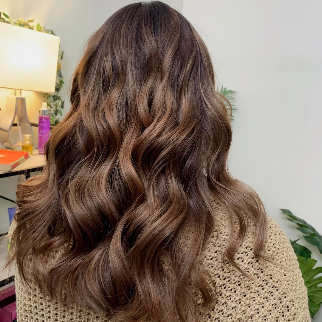 Stunning Caramel Brown Summer Hair 2026 Look Woman with long, flowing caramel brown summer hair 2026, wearing a breezy white linen dress and strappy sandals on a sunny beach.