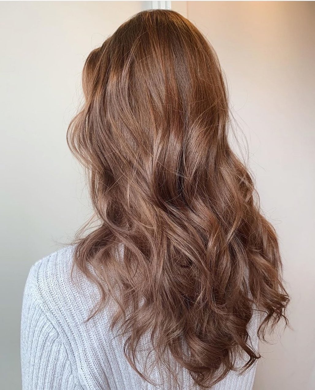 Caramel Brown Summer Hair 2026: Effortless Beach Waves Look A woman with radiant caramel brown summer hair 2026, styled in soft waves, smiles warmly. She wears a flowy white sundress with delicate embroidery, perfect for a casual daytime summer outing or beach vacation.