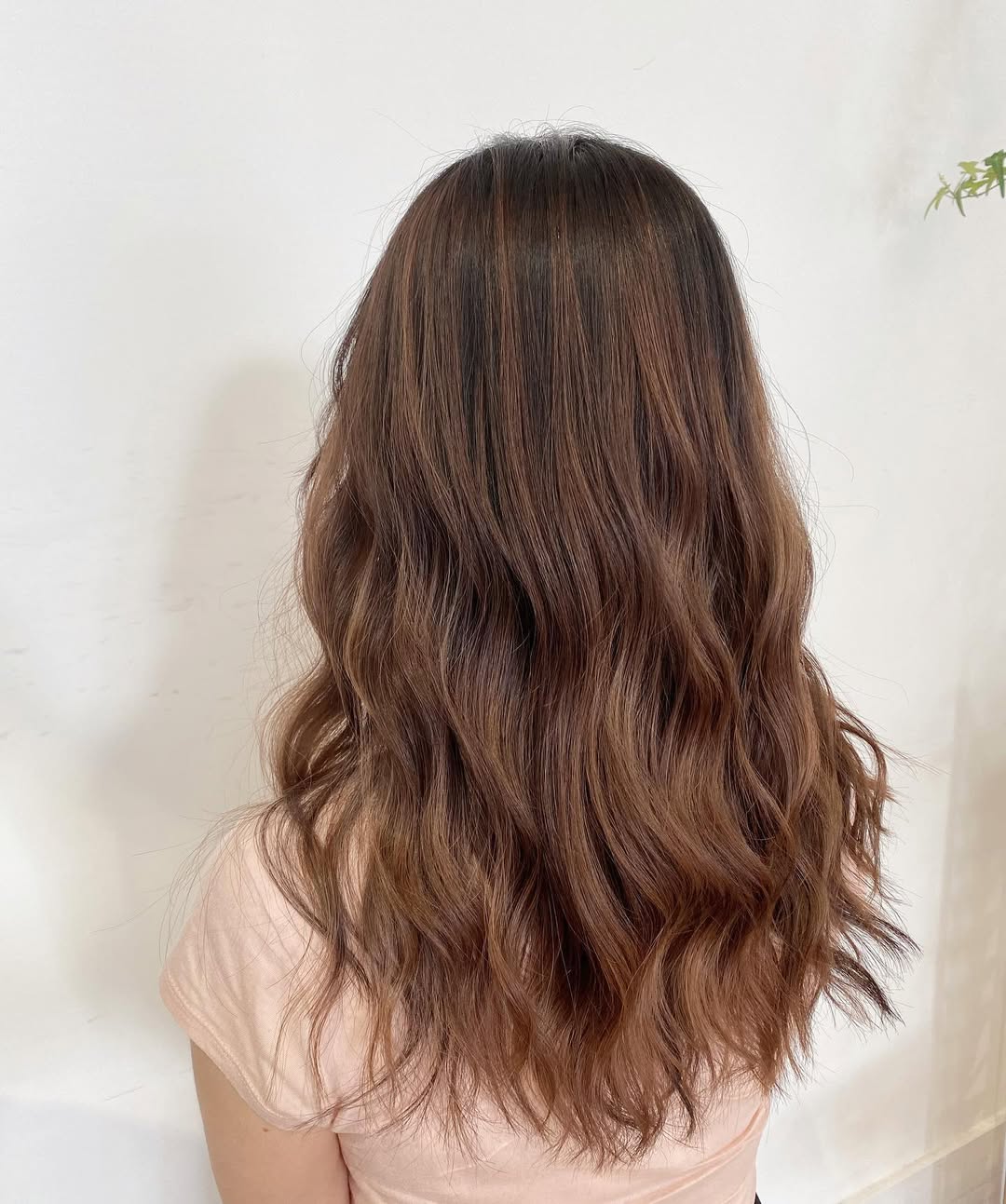 Chic Caramel Brown Summer Hair 2026 Style Close-up of a smiling woman with glossy caramel brown summer hair 2026, styled in soft waves. She wears a golden hoop earring and natural makeup, perfect for a chic daytime look.