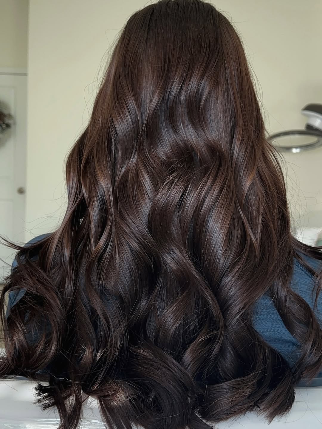Stunning Chocolate Brown Summer Hair 2026 Trends Close-up of a woman with long, glossy chocolate brown summer hair 2026, styled in soft waves with face-framing highlights, perfect for a casual day.