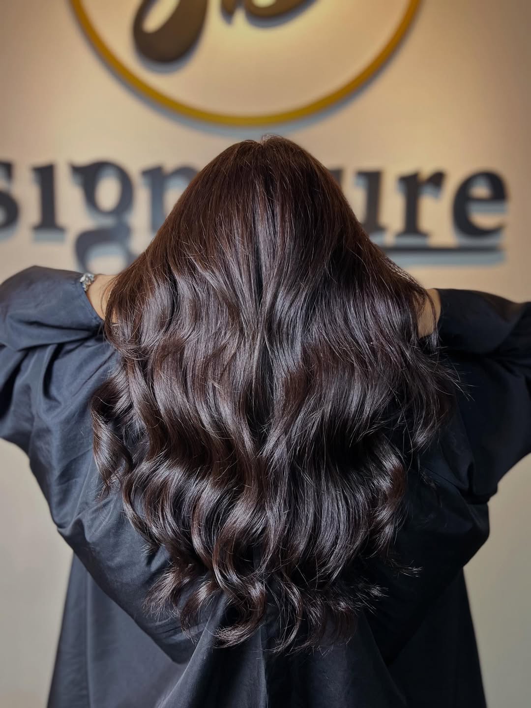 Chic Chocolate Brown Summer Hair 2026 Trends Close-up of a woman with shiny, wavy chocolate brown summer hair 2026, styled casually over her shoulders, against a blurred outdoor background.