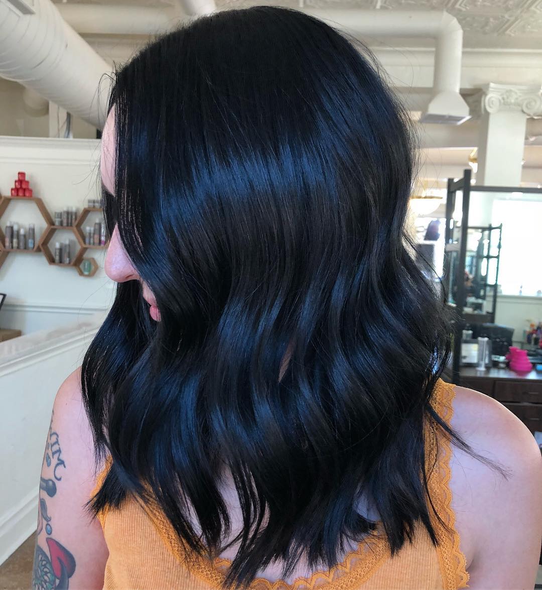Edgy Dark Hair Summer 2026: Chic Black Slip Dress Look A woman with edgy dark hair wearing a chic black slip dress and combat boots, perfect for a cool summer evening look in 2026. She exudes a fierce, effortless style.