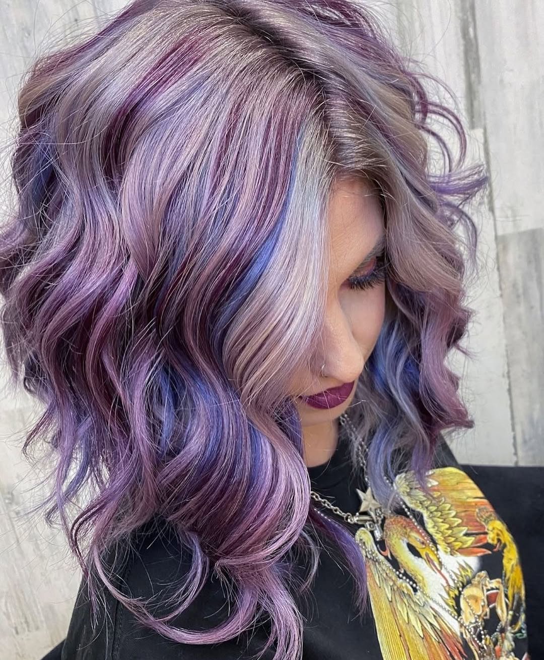 Close-up of a woman with vibrant pastel purple hair, styled in loose waves, enjoying summer outdoors. Perfect pastel hair color summer 2026 inspiration.