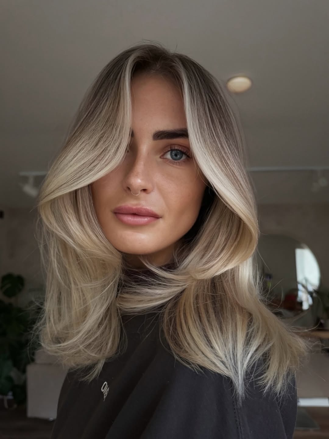 Close-up of a woman with soft ash blonde hair, styled in loose waves, complementing a soft summer palette. She wears a muted lavender top.