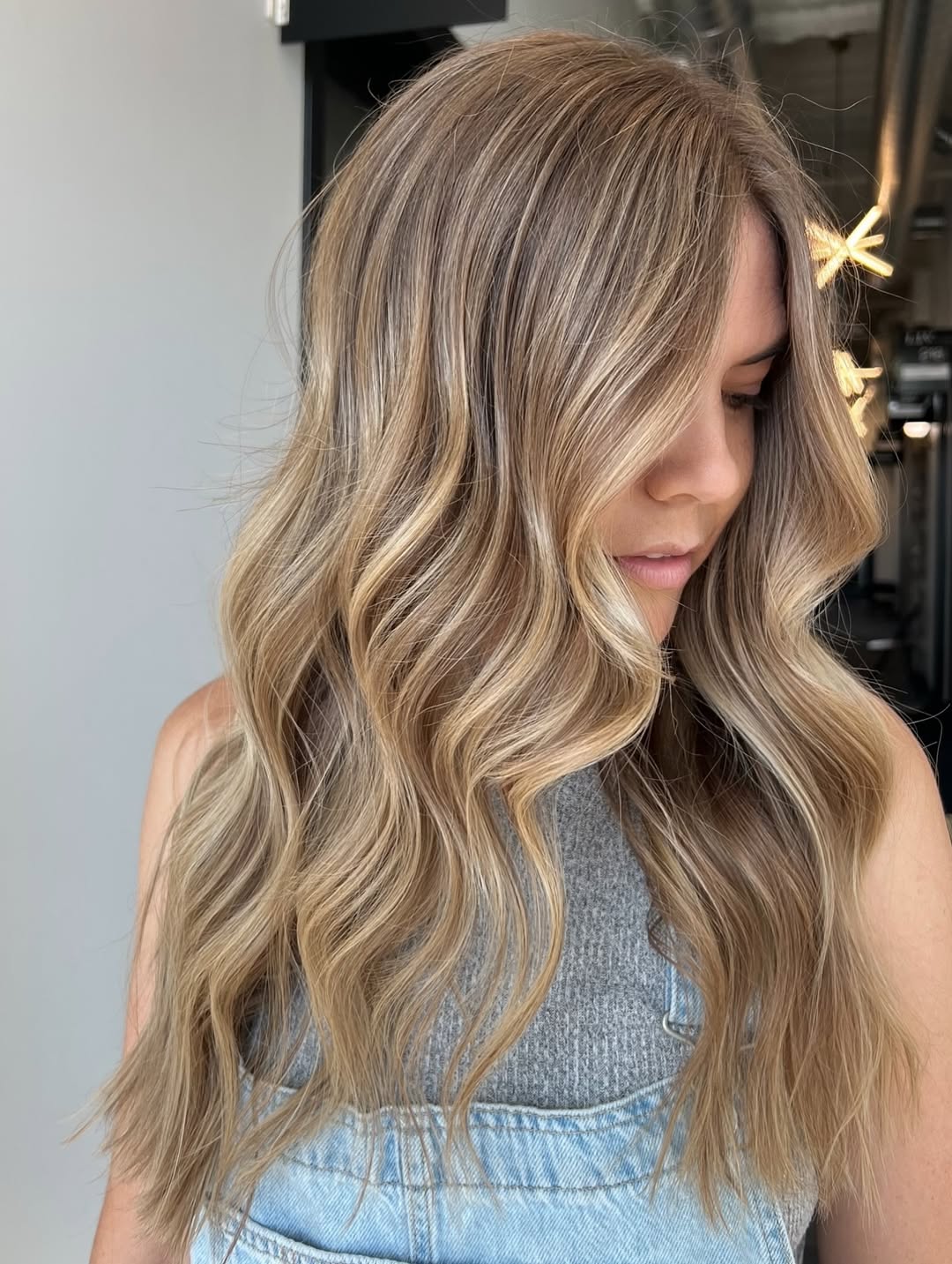 An elegant woman with soft summer palette hair 2026, featuring subtle blonde highlights framing her face, paired with a sophisticated light blue satin dress. Perfect for a chic evening event.