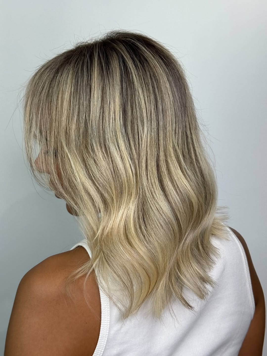 Woman with long, flowing brown hair, highlighting a soft summer palette hair 2026. Her hair has subtle, sun-kissed highlights, complementing her fair skin.