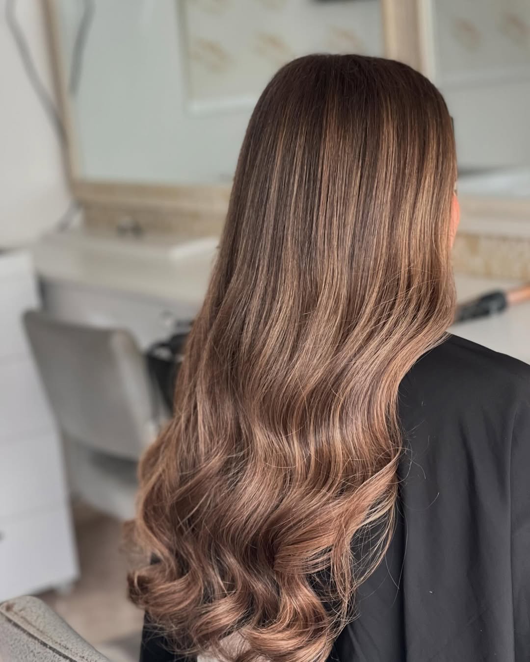 Close-up of a woman smiling, showcasing natural-looking subtle highlights in her summer hair, styled in loose waves, perfect for 2026 trends.