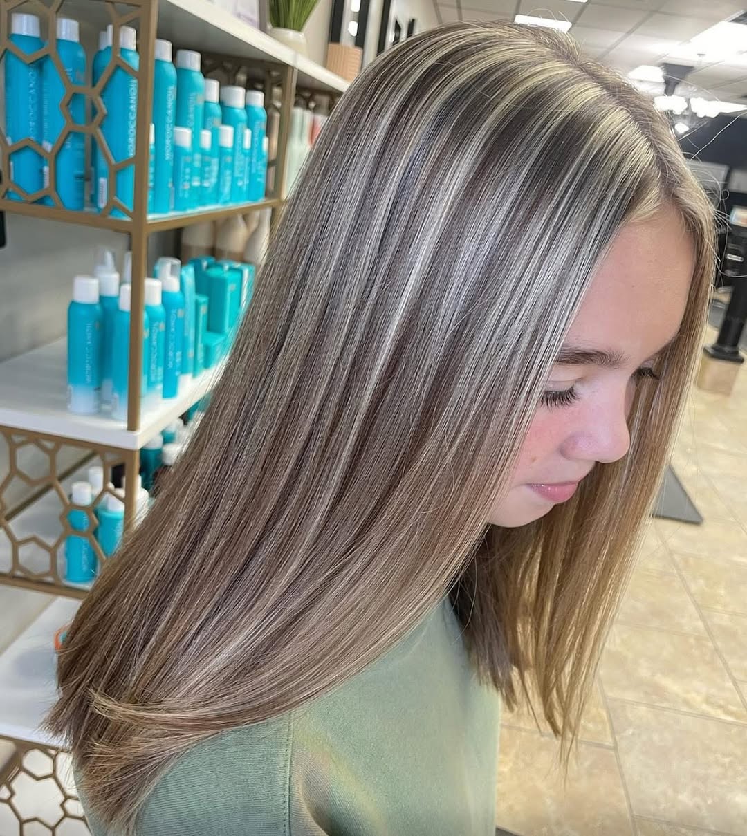 Close-up of a woman with long, sun-kissed brown hair featuring subtle highlights summer hair 2026, styled in soft waves.
