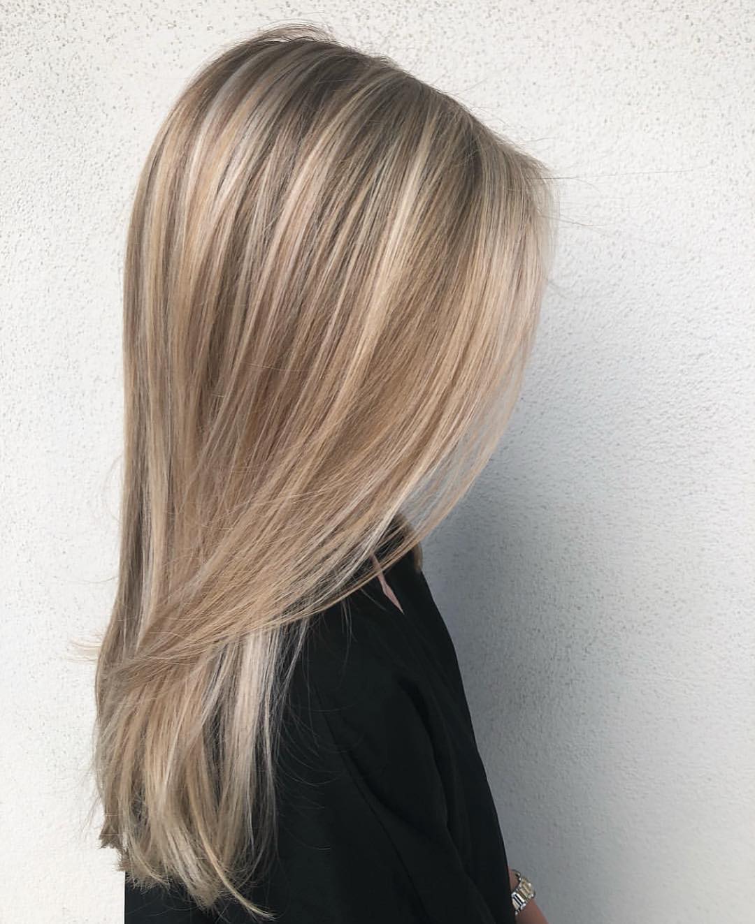 Woman with long, wavy blonde hair featuring subtle highlights, enjoying a bright summer day, perfect for effortless style.