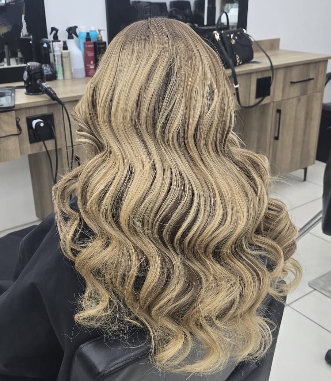 Woman with natural subtle highlights in her wavy brunette hair, glowing in the summer sun, perfect for a casual outdoor event.