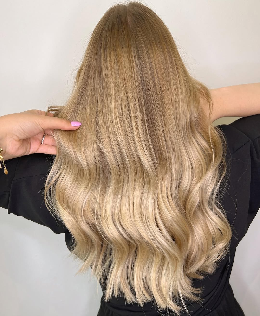 Close-up of a woman with vibrant golden blonde hair, showcasing a beautiful wavy style, perfect for summer hair color cute ideas 2026. Her hair has subtle sun-kissed highlights creating dimension and a fresh, bright look.