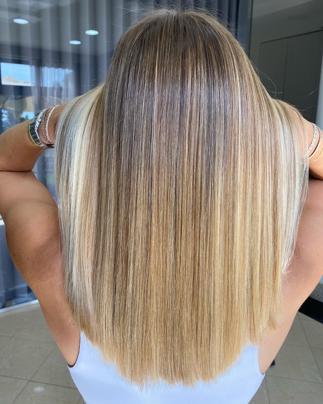 Close-up of a woman with vibrant, sun-kissed strawberry blonde hair, showcasing a cute summer hair color idea for a fun, beachy look.