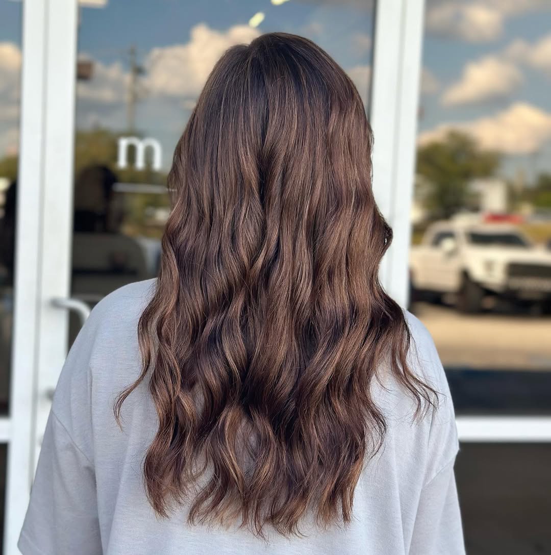 Stunning Summer Hair for Brunettes 2026 Close-up of a brunette woman with sun-kissed, natural waves, showcasing stunning summer hair for brunettes. Her chocolate brown hair catches the light beautifully, perfect for a warm weather look.