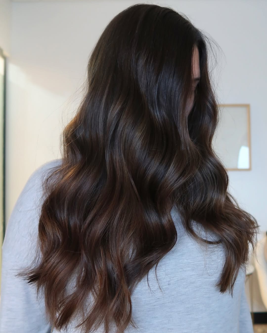 Stunning Wavy Summer Hair for Brunettes 2026! Beautiful brunette woman with flowing, natural waves, perfect summer hair for brunettes 2026. Her rich brown hair catches the light beautifully, showcasing a healthy sheen for a casual day out.