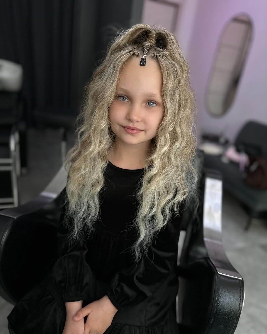 A smiling teenage girl with her blonde hair styled in a chic, half-up braided crown perfect for summer. This beautiful summer hairstyle for teenage girls accentuates her casual, sun-kissed look.